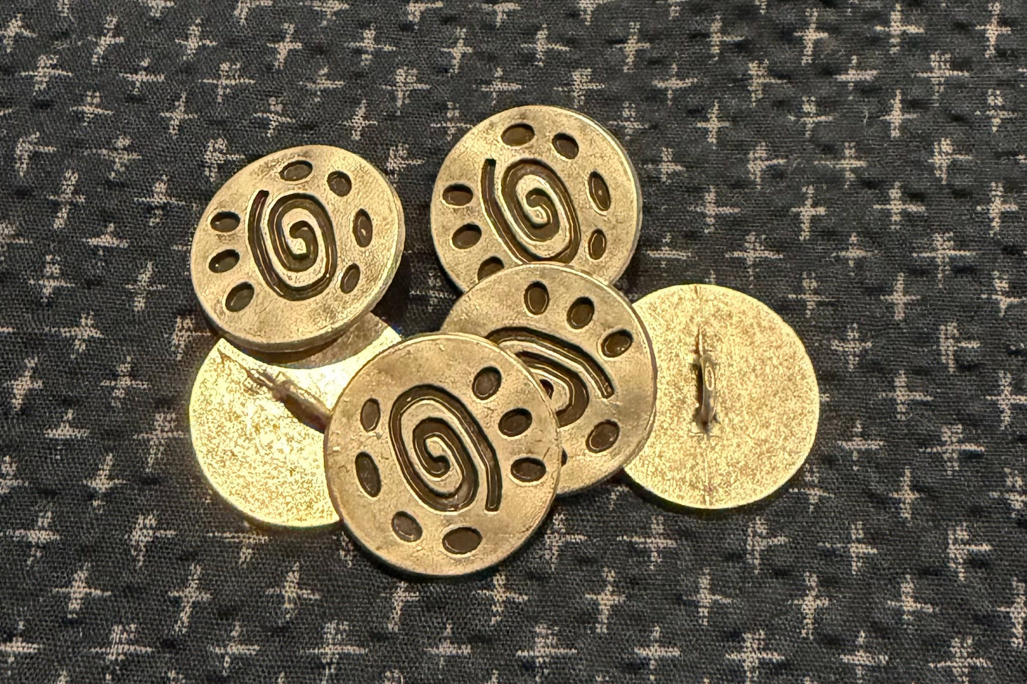 Silver round buttons on a textured dark fabric background