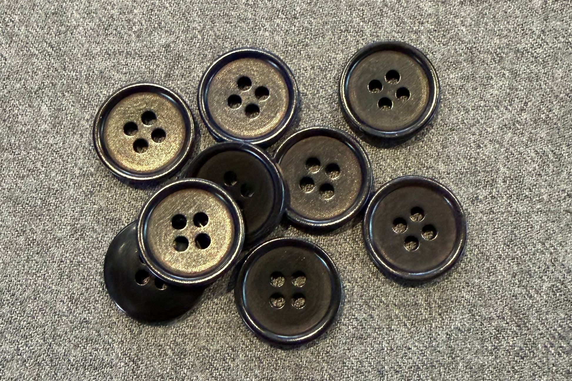 Group of black buttons on grey fabric
