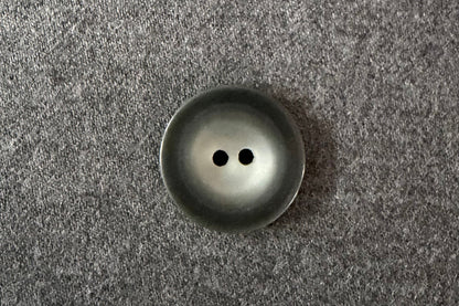 Dark grety button on a textured gray fabric background