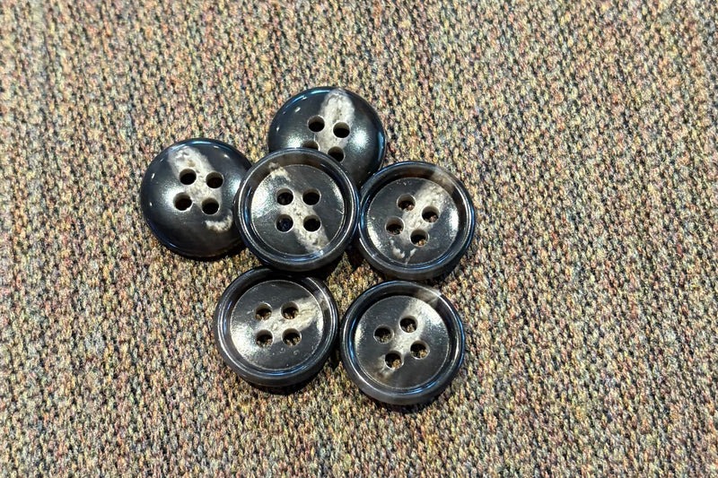 Set of six brown and tan buttons on a textured fabric background