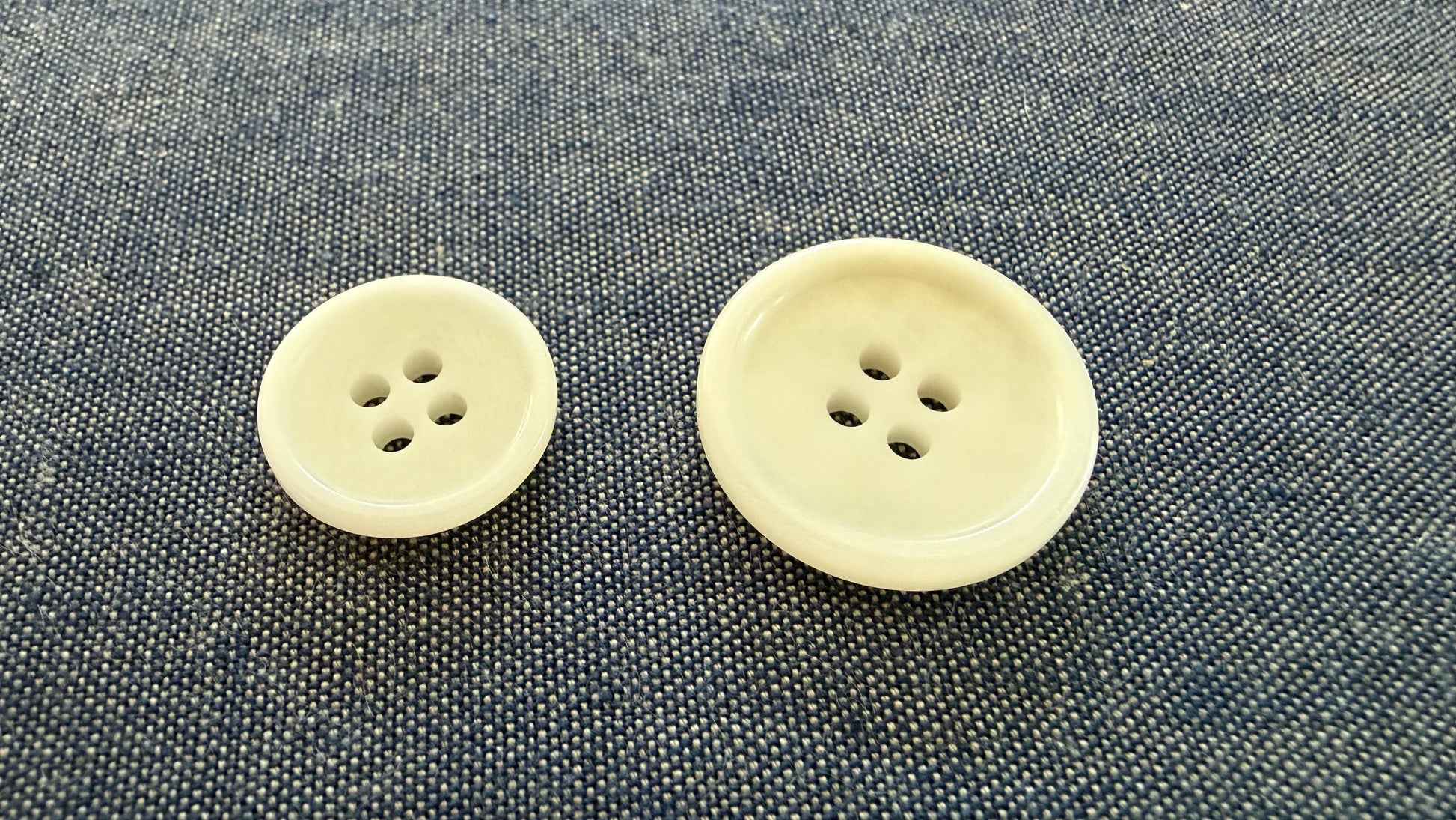 Two beige buttons on a textured gray fabric background