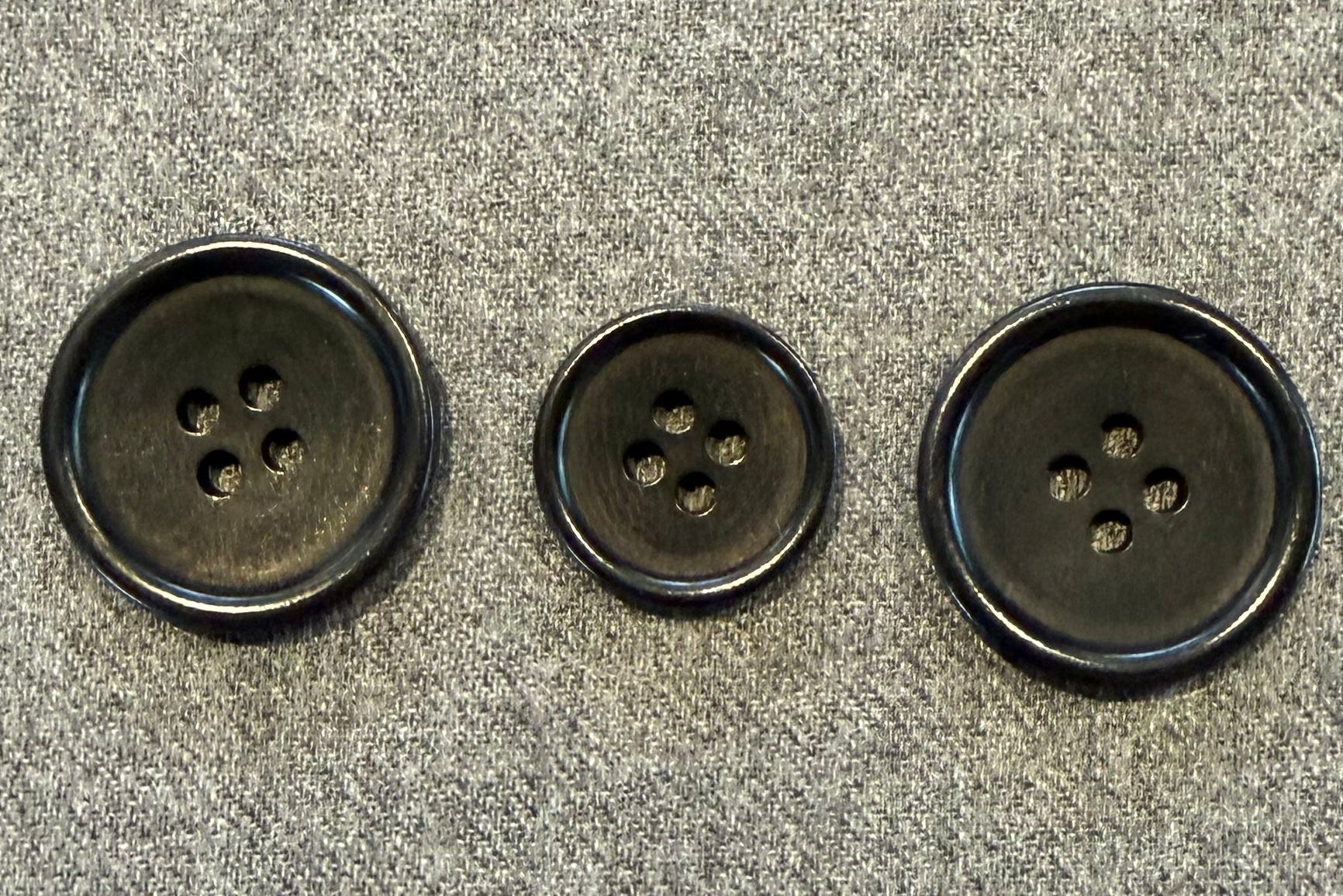 three black buttons on grey fabric