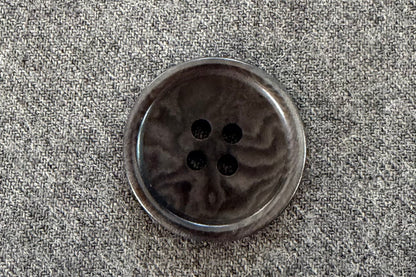 Grey button on a textured gray fabric background