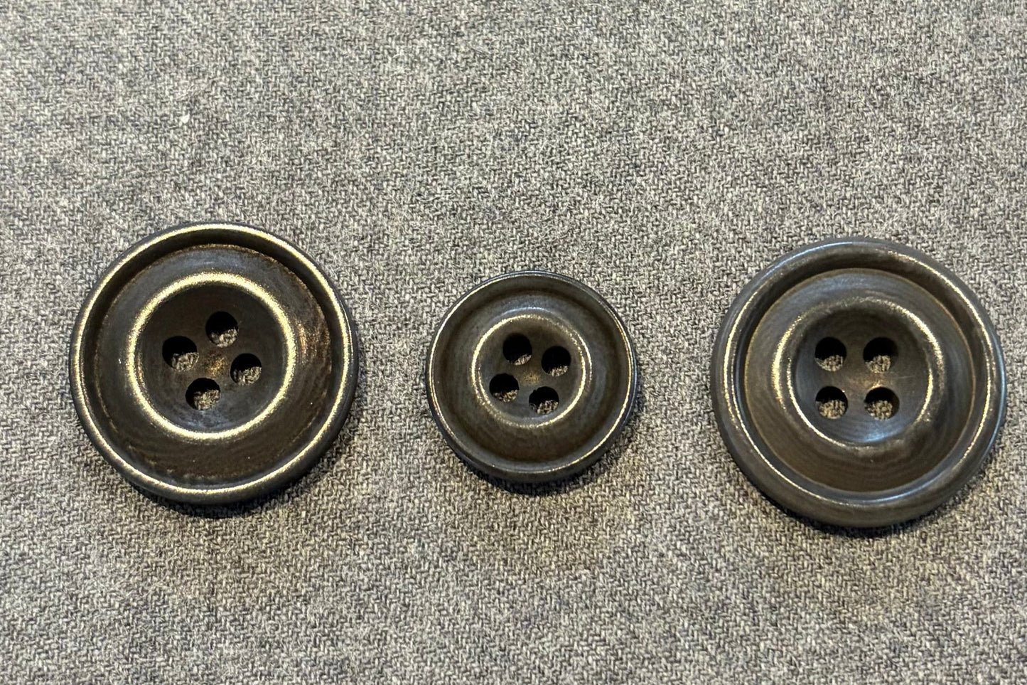 three grey buttons on a textured gray surface