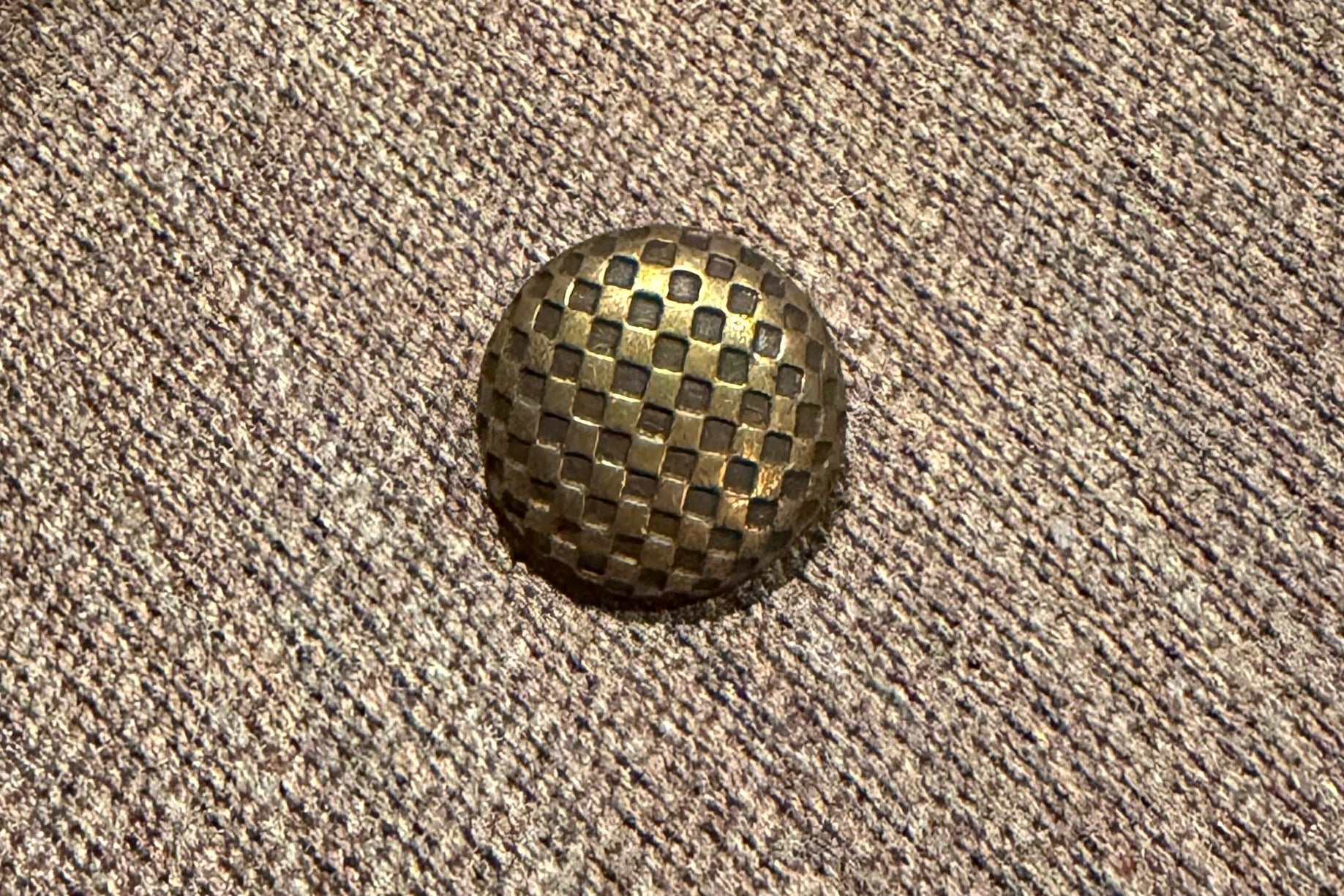 Metallic button on a textured fabric surface