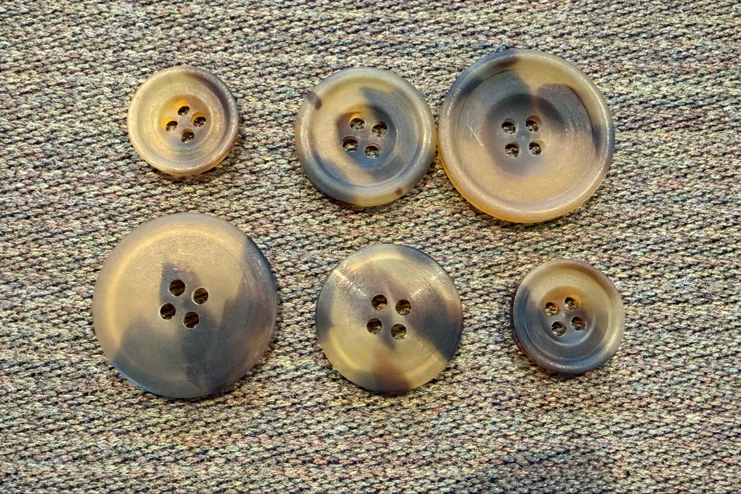 Set of six brown buttons on a textured gray surface