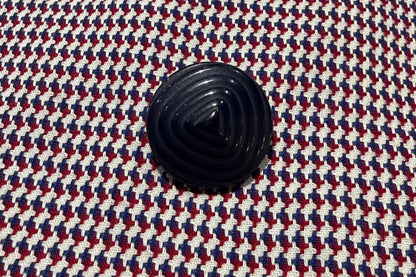 Close-up of a textured fabric with a navy blue button.