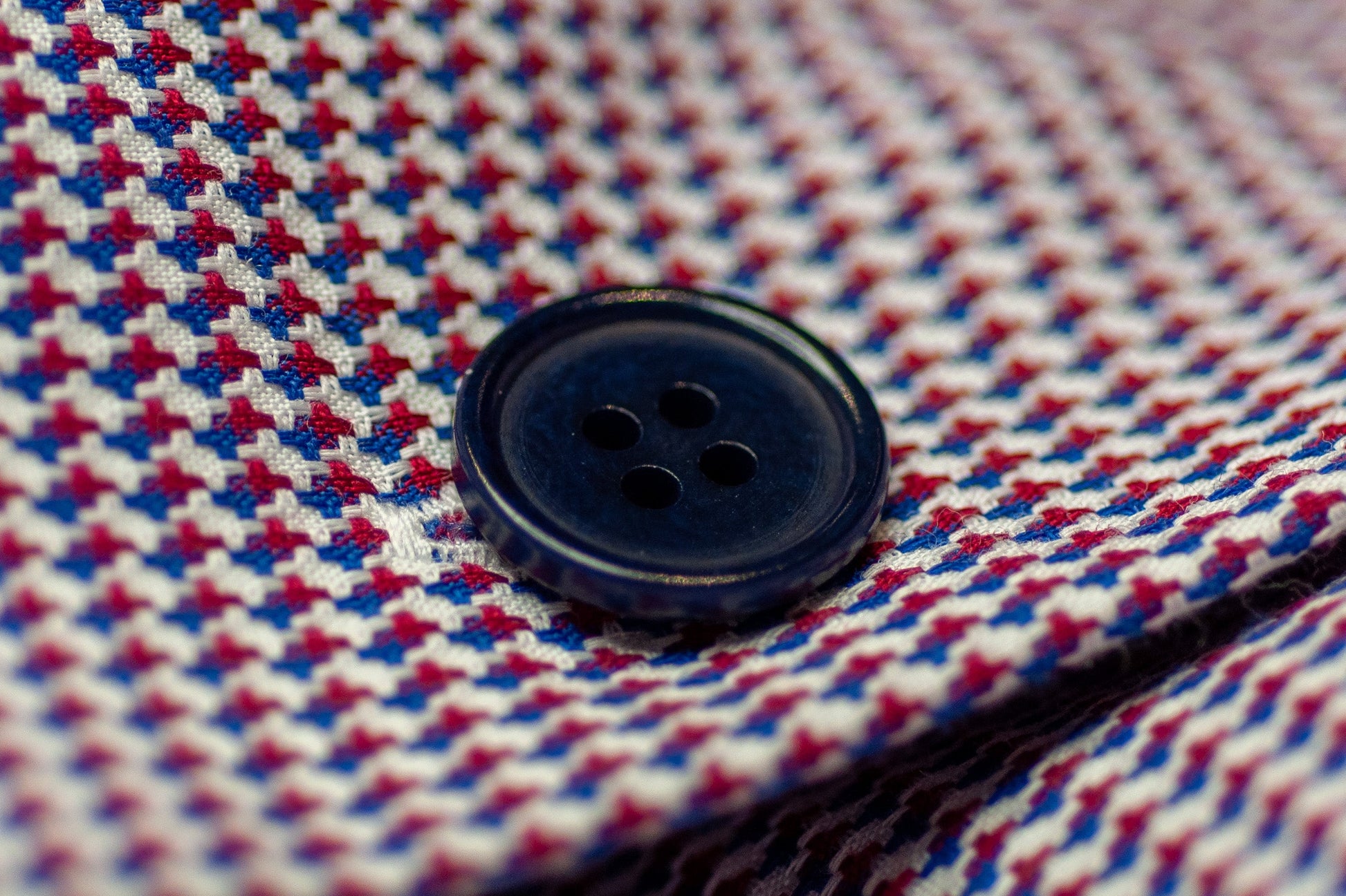 Close-up of a blue button on a red and blue checkered fabric