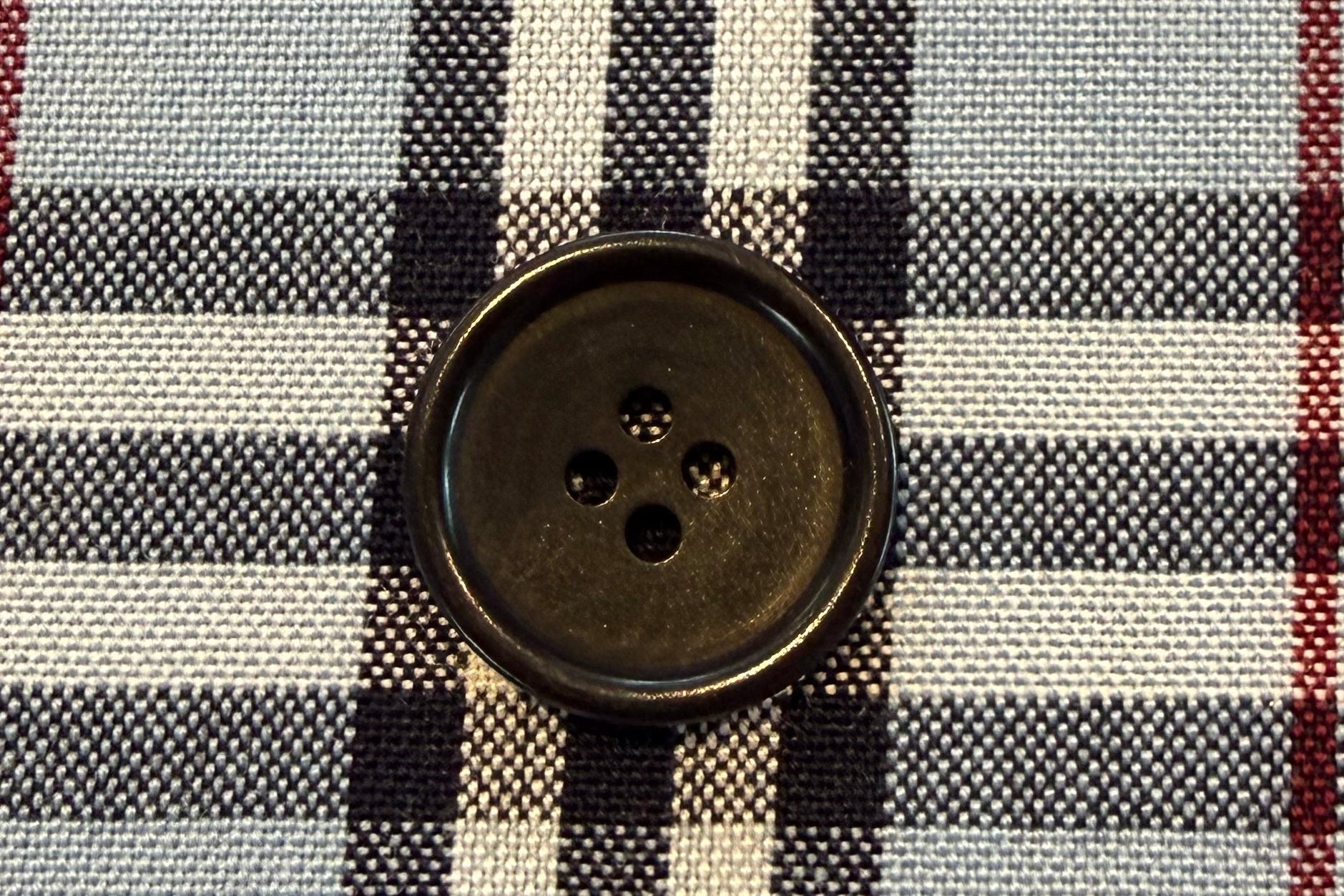 Close-up of a checkered fabric with a button on a gray background