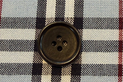 Close-up of a checkered fabric with a button on a gray background