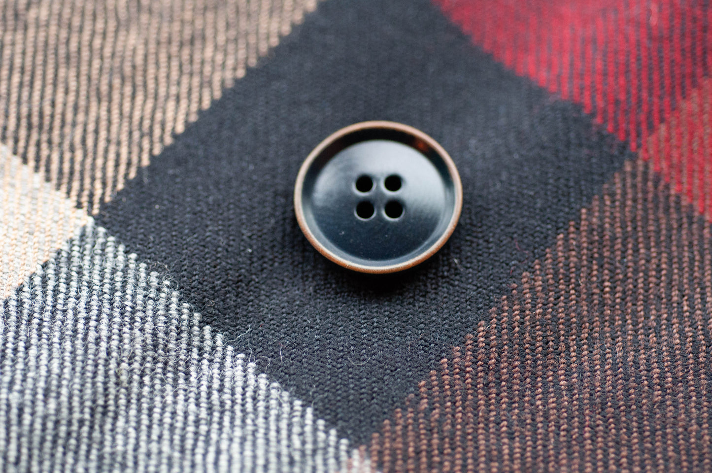 Close-up of a black button on plaid fabric