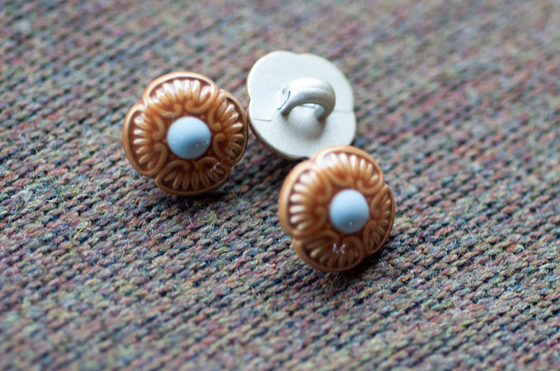 Three decorative floral buttons on a textured fabric background