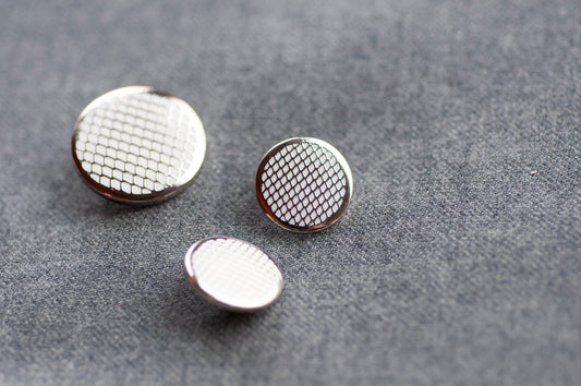 Three metallic buttons with textured surfaces on a gray background