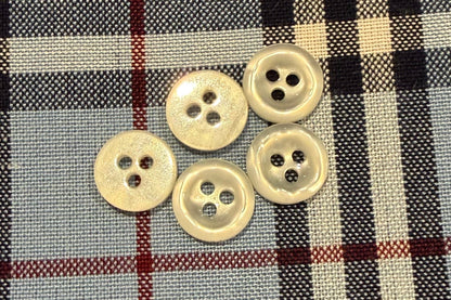 Five white buttons on a plaid fabric background