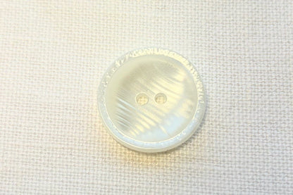 Close-up of a white button on a white fabric background