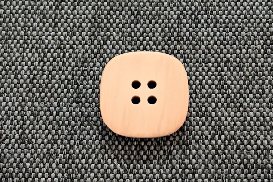 Tan button on a textured gray surface.