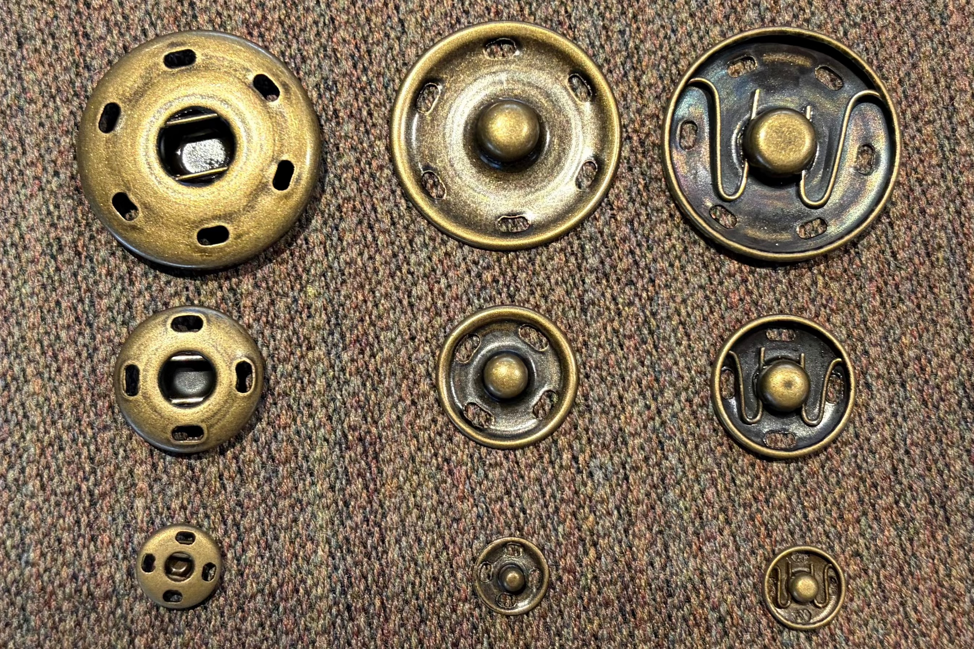 Set of brass snaps on a brown fabric background