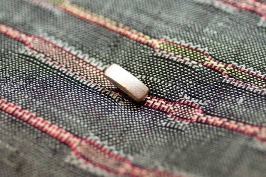 Close-up of a button on fabric with red and green thread